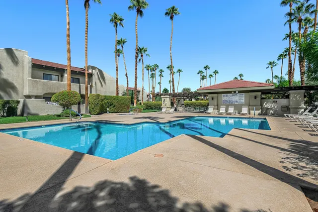 a view of a swimming pool with a yard and palm trees