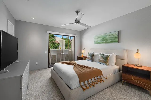 a bedroom with a bed and a flat tv screen on dresser
