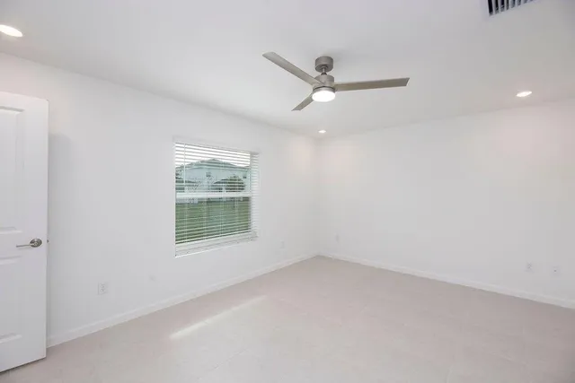 an empty room with a window and a fan