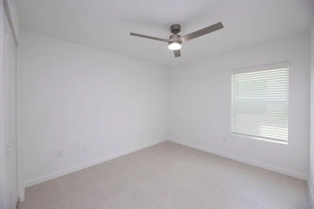 an empty room with a window and a fan