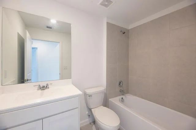 a bathroom with a bathtub shower sink vanity mirror and toilet