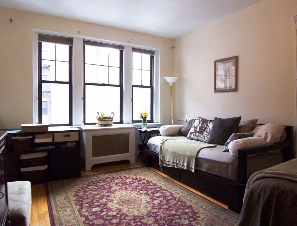 a living room with furniture and a dresser next to a window