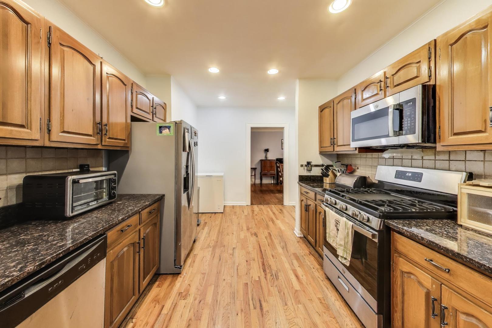 2322 West Farwell Avenue, Unit 1W Chicago, IL 60645 - Photo 20 of 28 a kitchen with stainless steel appliances granite countertop a stove top oven a sink dishwasher a refrigerator and cabinets with wooden floor