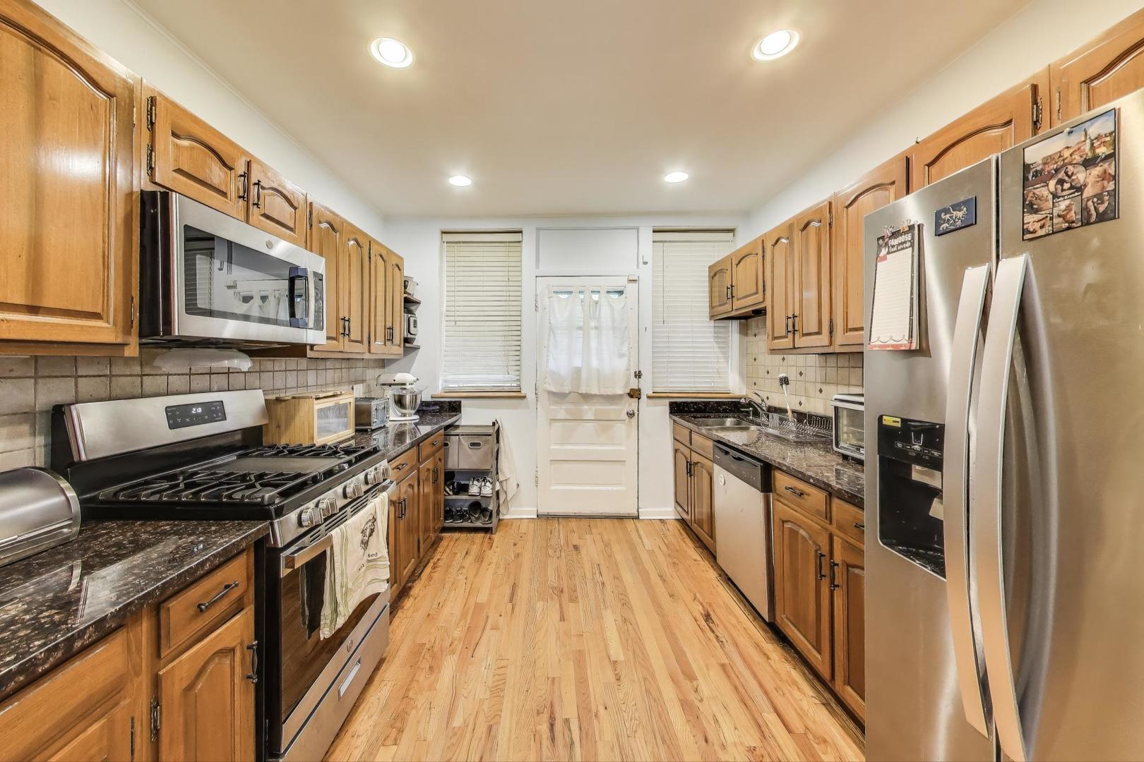 2322 West Farwell Avenue, Unit 1W Chicago, IL 60645 - Photo 21 of 28 a kitchen with stainless steel appliances granite countertop a stove top oven a sink dishwasher a refrigerator and cabinets with wooden floor