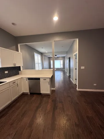 a large white kitchen with a refrigerator a sink dishwasher a stove and white countertops with wooden floor