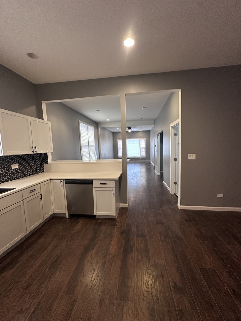 6715 South Sangamon Street Chicago, IL 60621 - Photo 12 of 43 a large white kitchen with a refrigerator a sink dishwasher a stove and white countertops with wooden floor