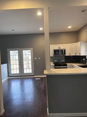 a large kitchen with stainless steel appliances a sink a stove and wooden floor