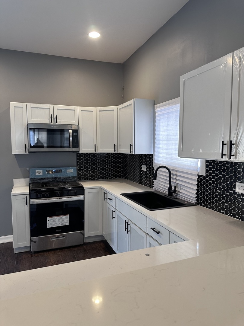 6715 South Sangamon Street Chicago, IL 60621 - Photo 8 of 43 a kitchen with granite countertop a sink and a stove top oven