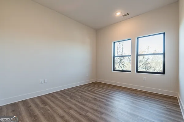 an empty room with wooden floor and windows