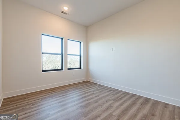 an empty room with wooden floor and windows