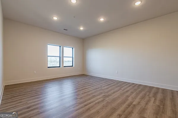 an empty room with wooden floor and windows