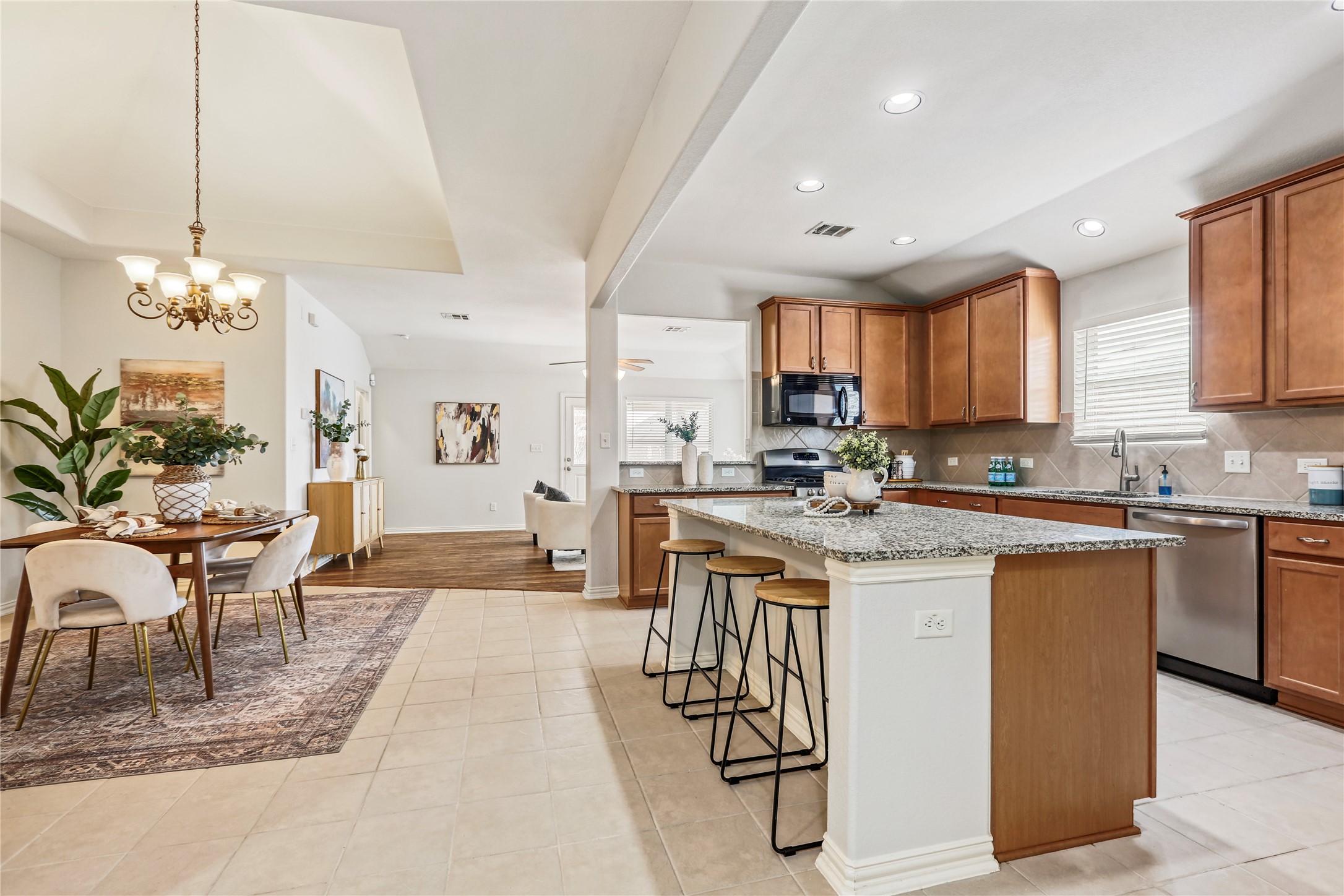 3900 Brean Down Road Pflugerville, TX 78660 - Photo 4 of 35 a kitchen with stainless steel appliances kitchen island granite countertop a stove a sink a dining table and chairs