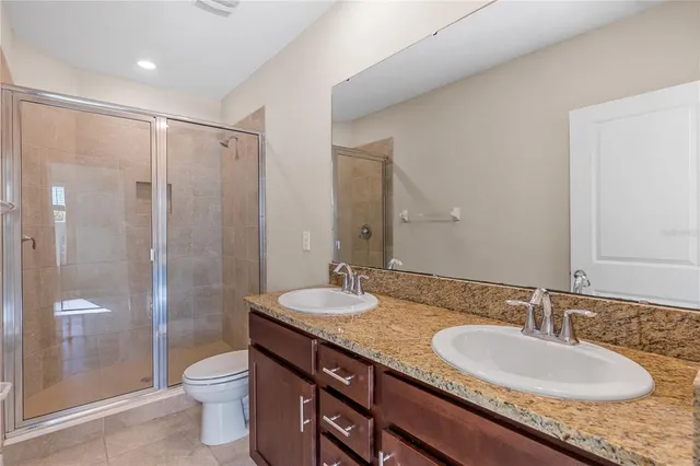 a bathroom with a granite countertop double vanity sink toilet and shower