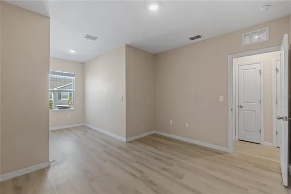a view of an empty room with wooden floor and closet