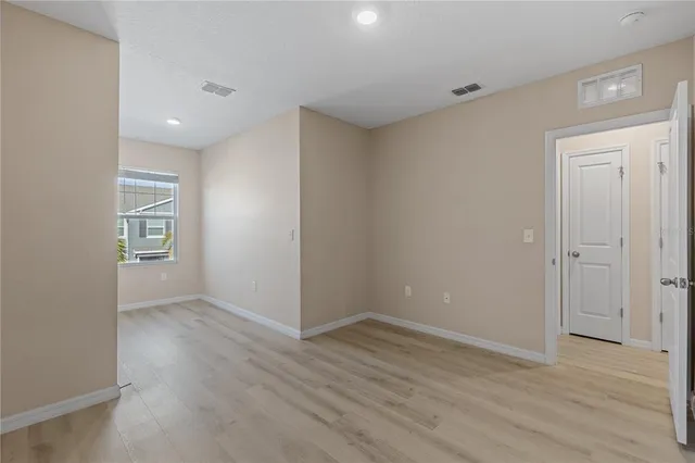 a view of an empty room with wooden floor and closet