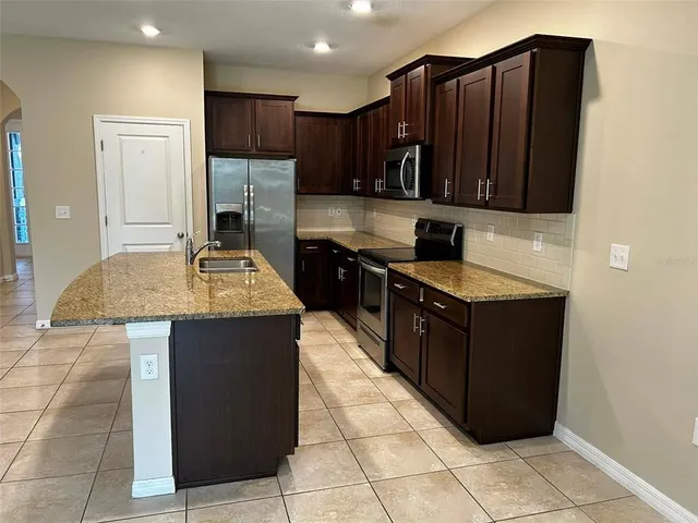 a kitchen with stainless steel appliances granite countertop wooden cabinets a granite counter top and a stove