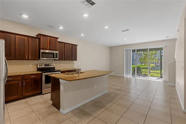 a kitchen with stainless steel appliances granite countertop a stove top oven a sink dishwasher and a refrigerator
