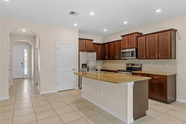a kitchen with stainless steel appliances granite countertop a stove top oven a sink and a refrigerator