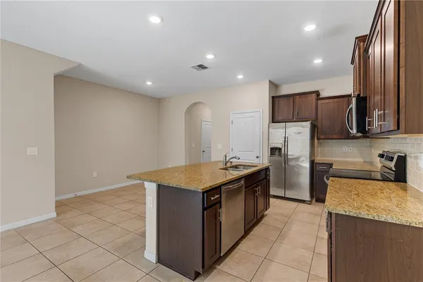 a kitchen with stainless steel appliances granite countertop a sink a stove and a refrigerator