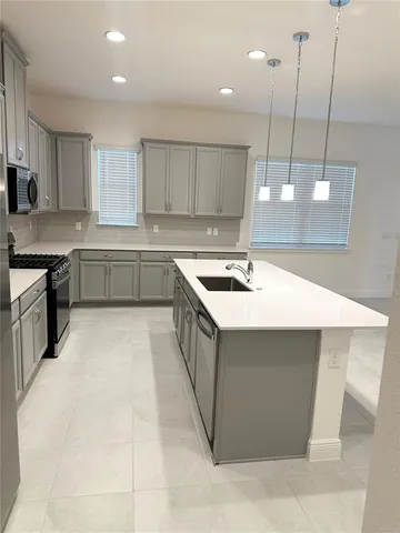 a kitchen with a sink a counter top space stainless steel appliances and cabinets
