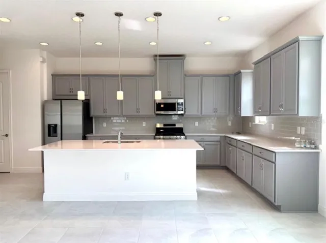 a large kitchen with kitchen island a white wooden cabinets with a sink and dishwasher