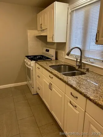a kitchen with stainless steel appliances granite countertop a sink stove and cabinets