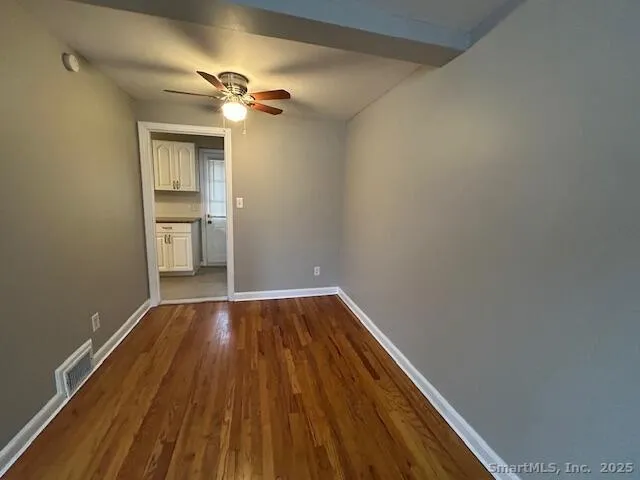 a view of a room with wooden floor a ceiling fan and a window