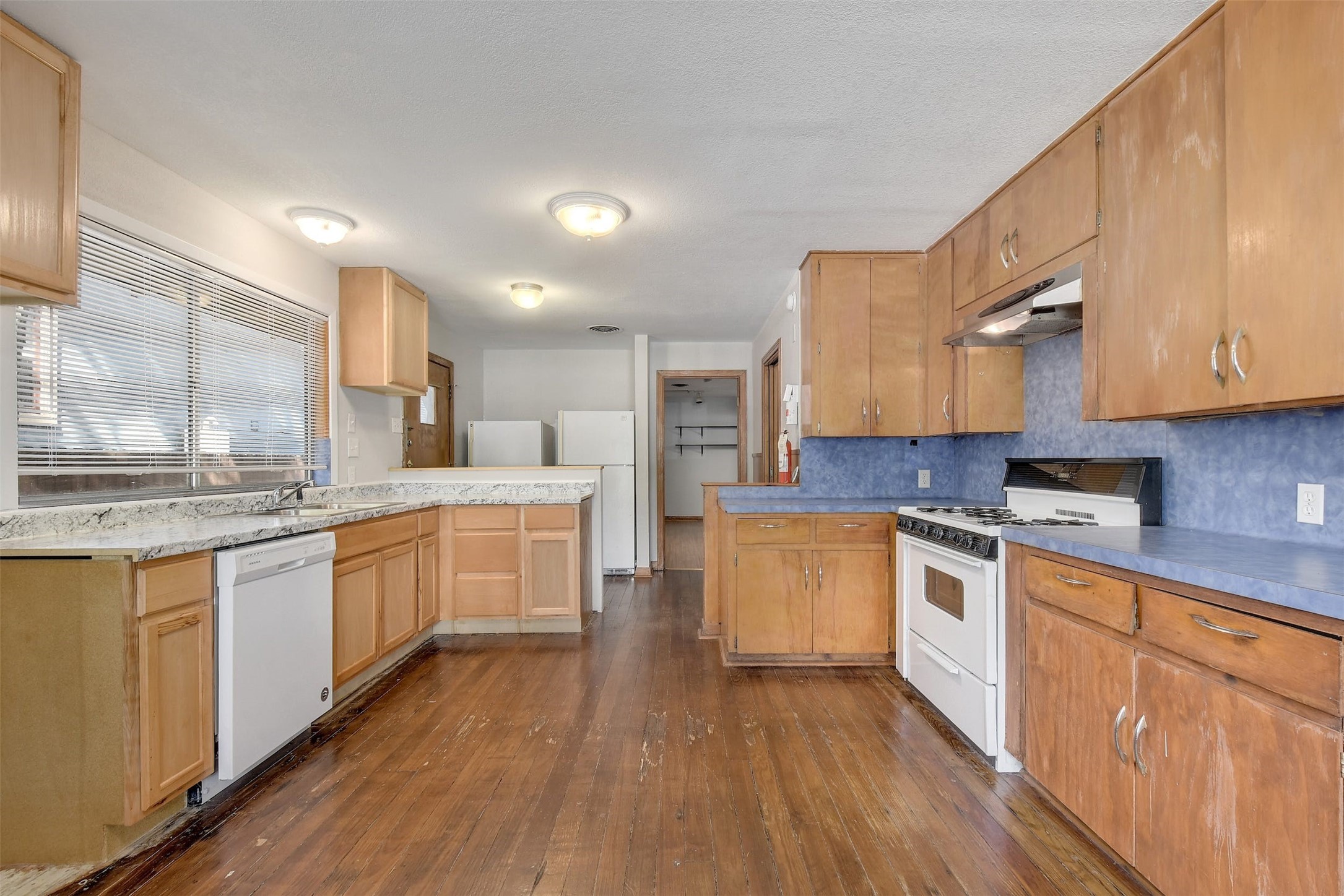 4306 Avenue B Austin, TX 78751 - Photo 12 of 34 a large kitchen with stainless steel appliances granite countertop a stove top oven a sink dishwasher and white cabinets with wooden floor