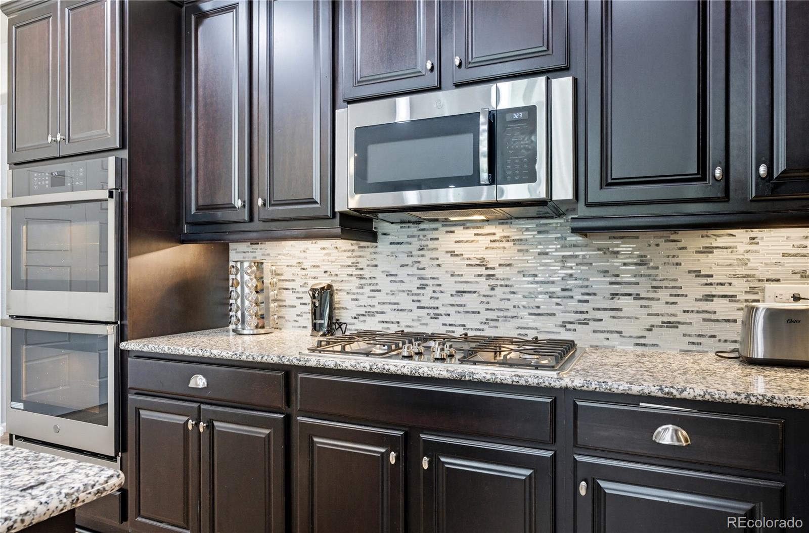 5740 Berry Ridge Wy. Castle Rock, CO 80104 - Photo 15 of 38 a kitchen with granite countertop a sink stainless steel appliances and cabinets