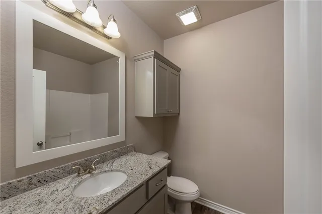 a bathroom with a granite countertop sink toilet and mirror