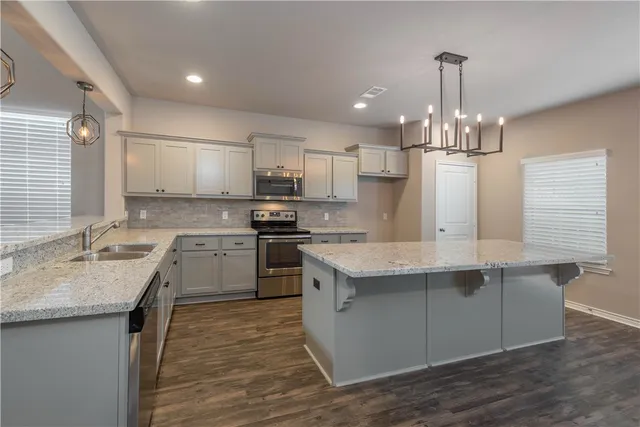 a kitchen with kitchen island granite countertop a sink stainless steel appliances and cabinets