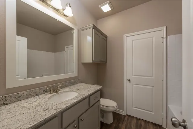 a bathroom with a granite countertop sink toilet and mirror