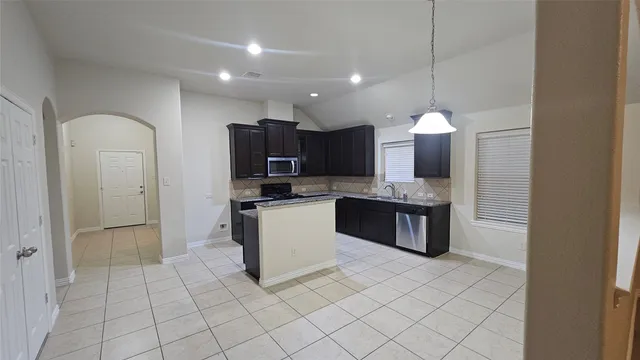 a large kitchen with a large counter top space appliances and cabinets