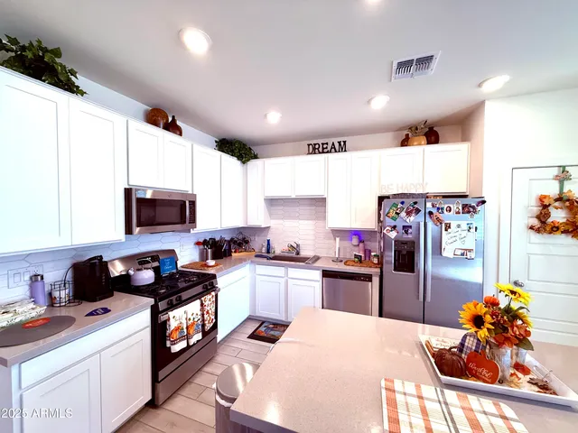 a kitchen with stainless steel appliances kitchen island granite countertop a refrigerator stove top oven and sink