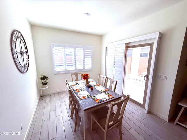 a dining room with wooden floor a chandelier a wooden table and chairs