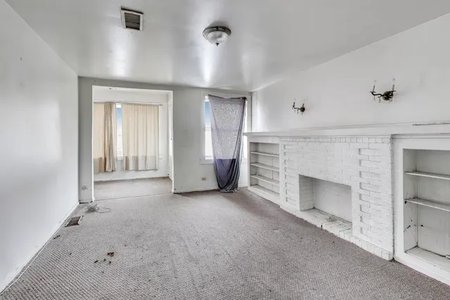 an empty room with a fireplace and windows