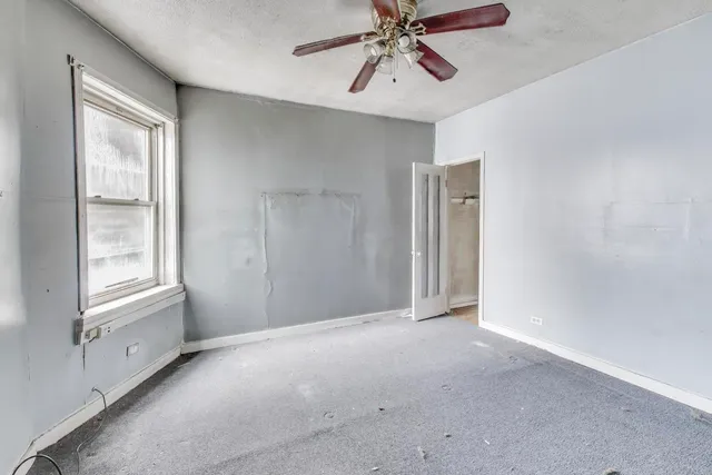 a view of an empty room with chandelier fan and window