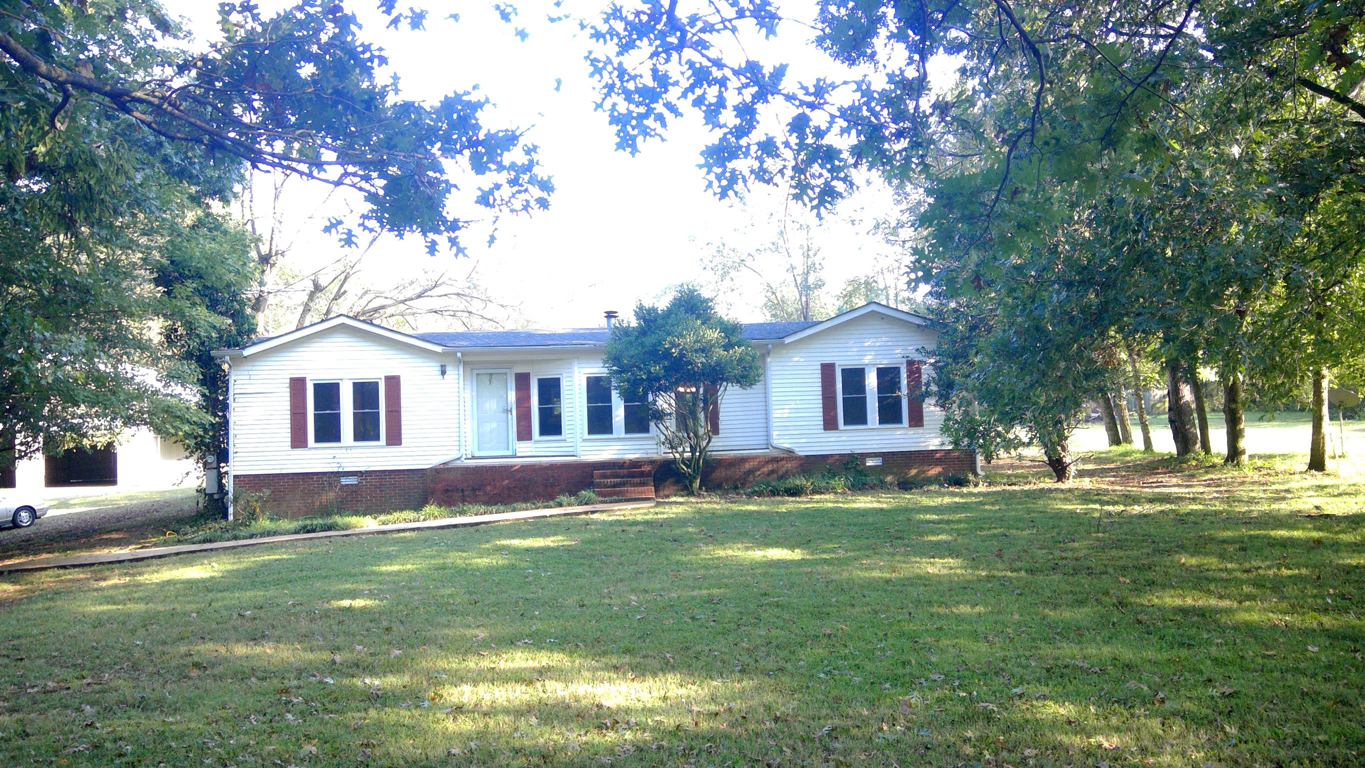 a front view of a house with a garden and trees