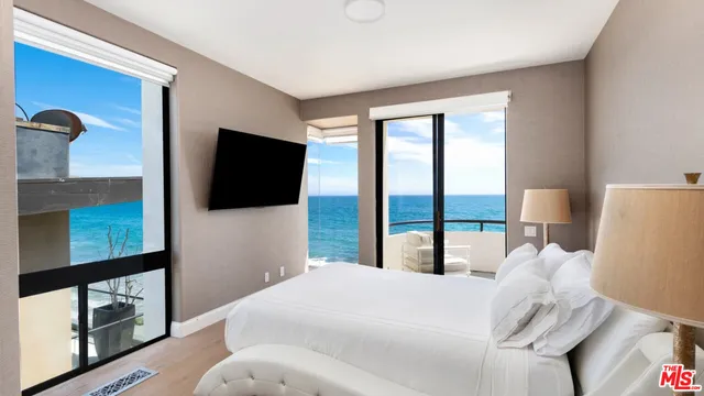 a bedroom with a bed and a flat tv screen next to a window