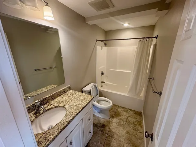 a bathroom with a granite countertop sink toilet and shower