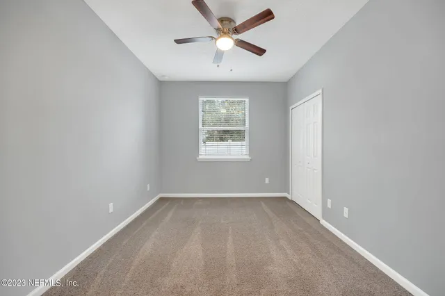 an empty room with a window and a fan