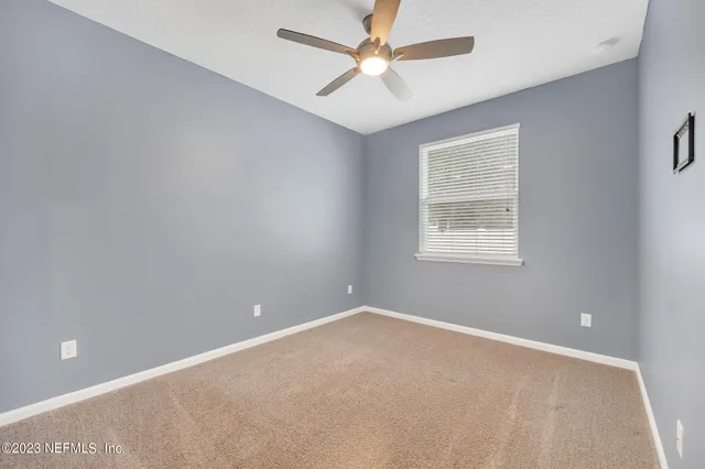a view of an empty room and chandelier fan