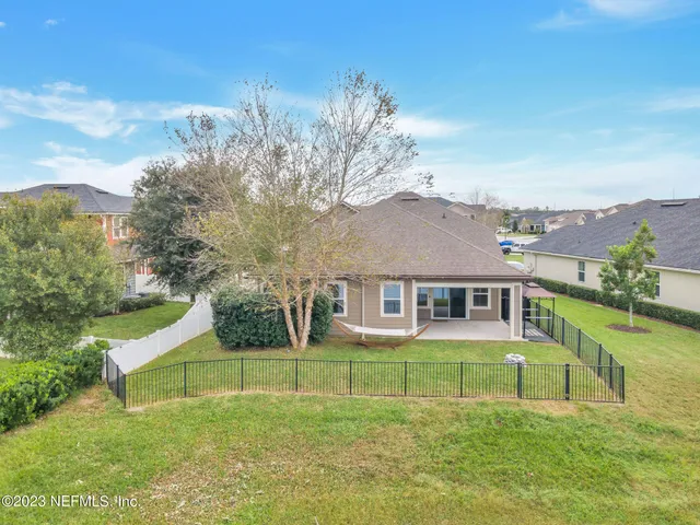 a view of a house with a big yard potted plants and a large tree