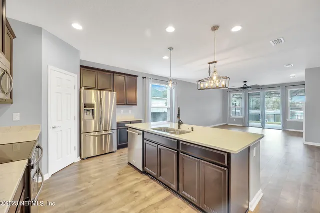 a kitchen with a stove a refrigerator a sink and dishwasher with wooden floor