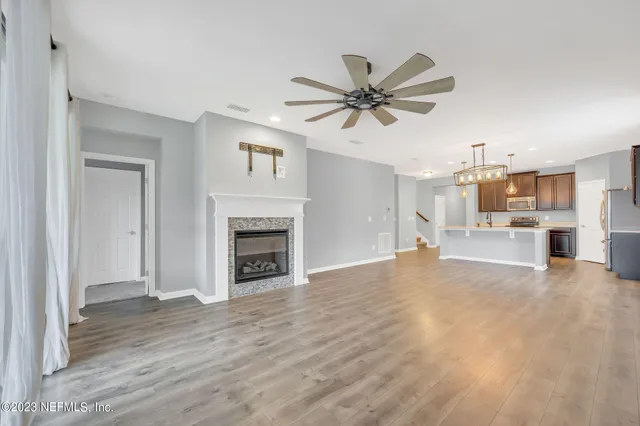 a view of a livingroom with a fireplace a chandelier fan and wooden floor