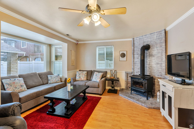 1402 South 1470th Street East Provo, UT 84606 - Photo 4 of 21 Living area with ceiling fan, ornamental molding, light wood-type flooring, and a wood stove