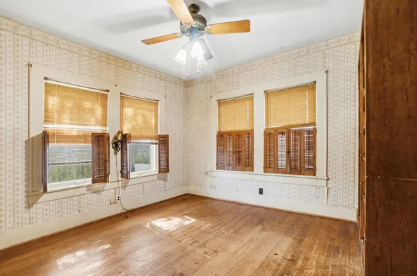 a view of an empty room with a window and wooden floor