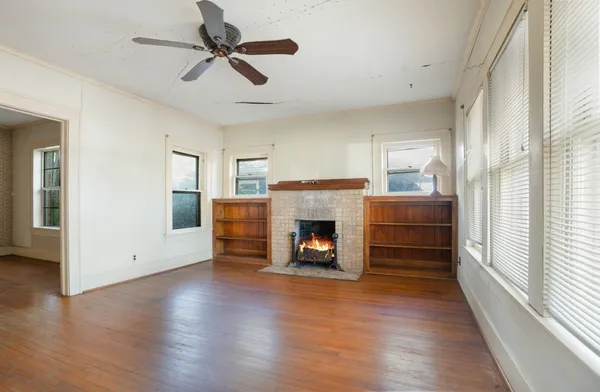 a view of a livingroom with a fireplace a ceiling fan and windows