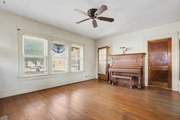 a view of empty room with wooden floor and fan