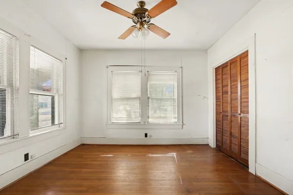 a view of an empty room with a window and wooden floor